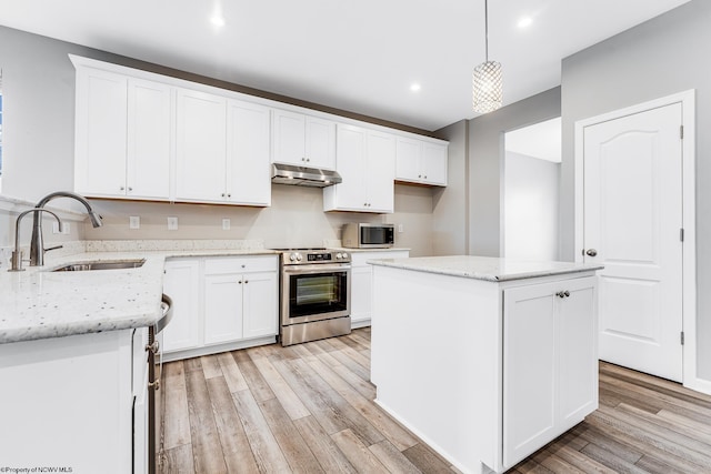 kitchen with sink, light stone counters, hanging light fixtures, appliances with stainless steel finishes, and a kitchen island