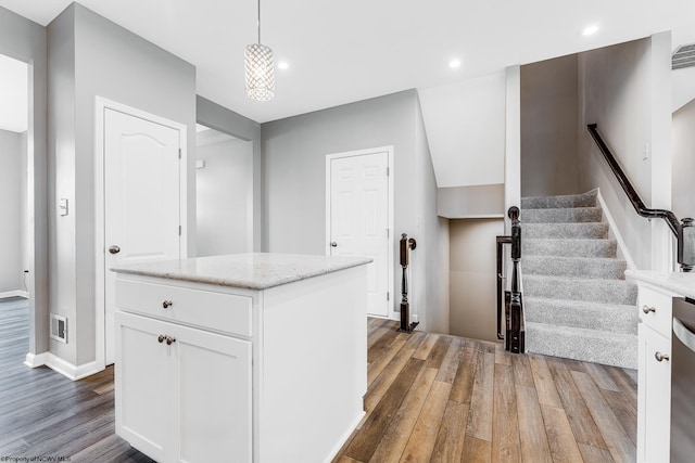 kitchen featuring white cabinetry, hanging light fixtures, wood-type flooring, and a center island