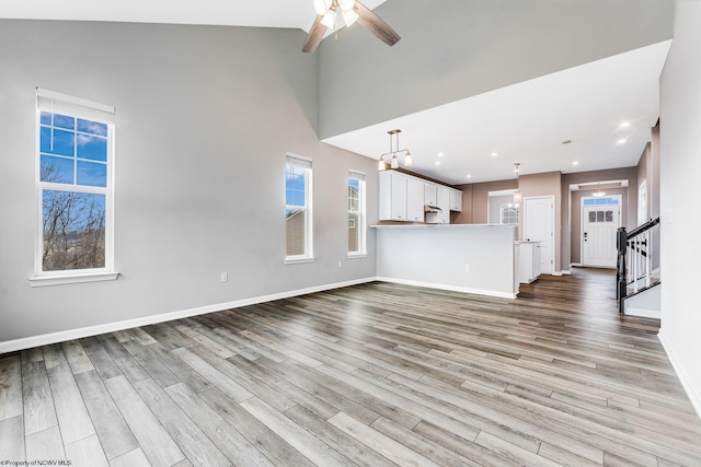 unfurnished living room with ceiling fan, high vaulted ceiling, and light hardwood / wood-style flooring