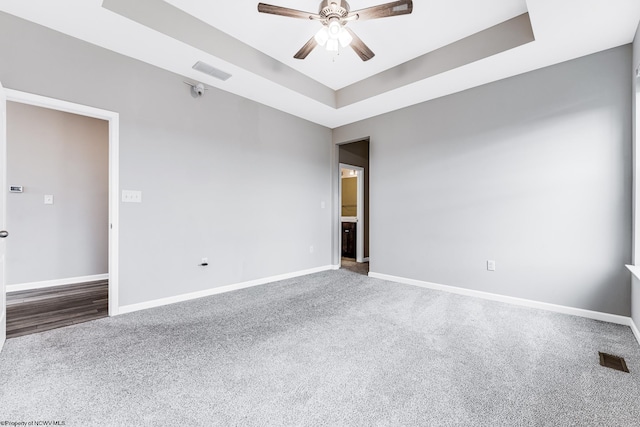 carpeted empty room featuring ceiling fan and a tray ceiling