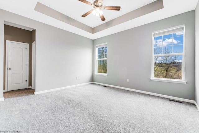 carpeted empty room featuring ceiling fan and a tray ceiling