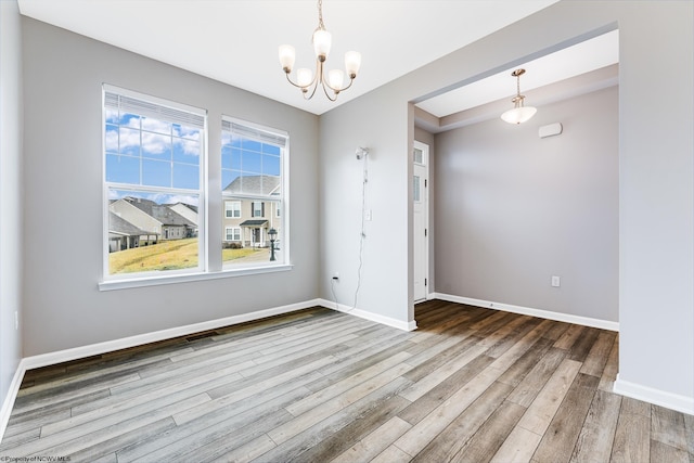 empty room with hardwood / wood-style flooring and a chandelier