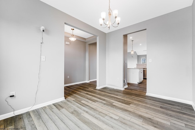 unfurnished dining area with wood-type flooring and an inviting chandelier