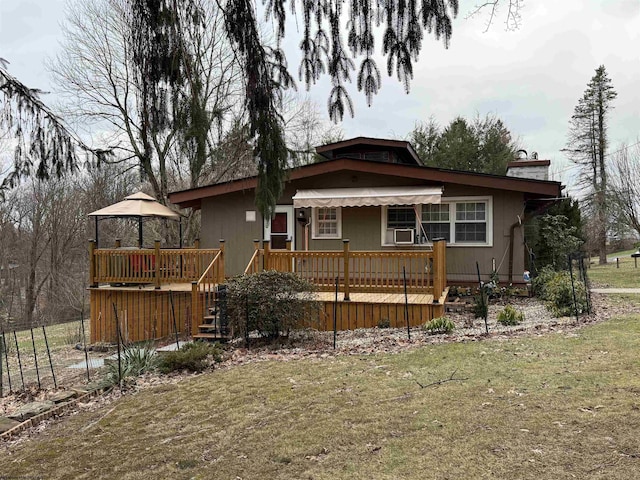 rear view of property featuring a wooden deck and a lawn