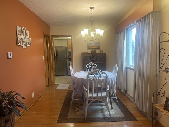 dining room with light hardwood / wood-style floors and a notable chandelier