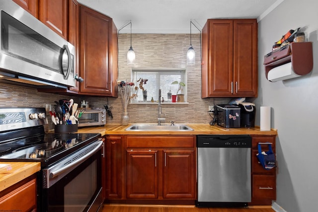 kitchen featuring tasteful backsplash, appliances with stainless steel finishes, sink, and hanging light fixtures