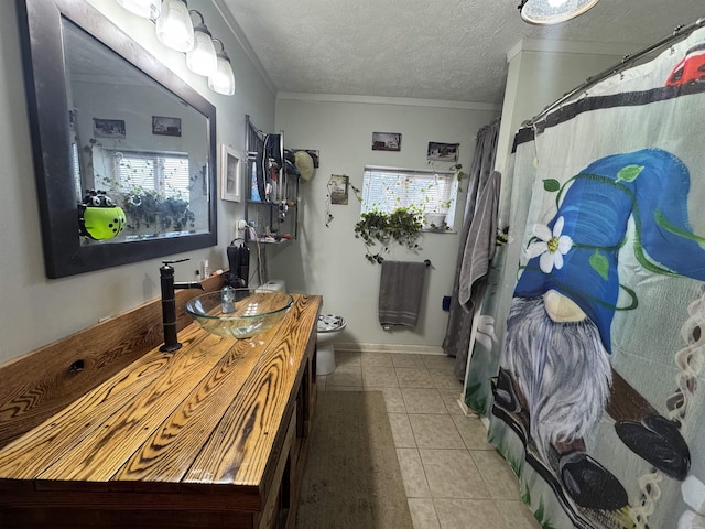 bathroom with tile patterned flooring, ornamental molding, vanity, toilet, and a textured ceiling