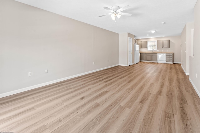 unfurnished living room with sink, ceiling fan, and light wood-type flooring