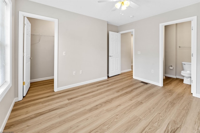 unfurnished bedroom with a walk in closet, ensuite bath, a closet, ceiling fan, and light hardwood / wood-style floors