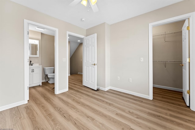 unfurnished bedroom featuring connected bathroom, sink, light hardwood / wood-style flooring, a spacious closet, and a closet