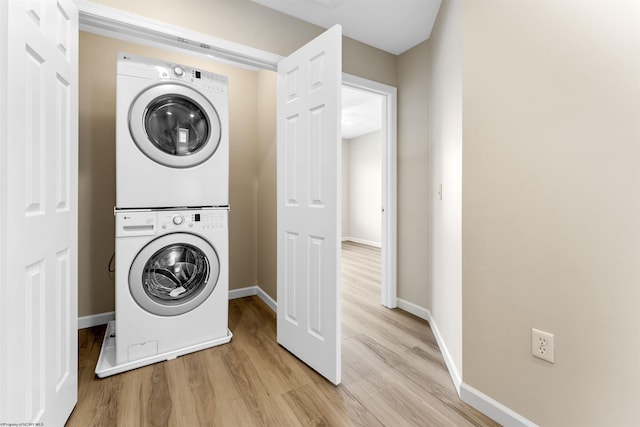 washroom with light hardwood / wood-style flooring and stacked washer / dryer