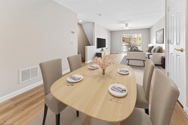 dining room featuring ceiling fan, light hardwood / wood-style floors, and a textured ceiling