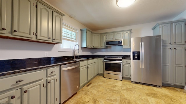 kitchen with appliances with stainless steel finishes, sink, and dark stone counters