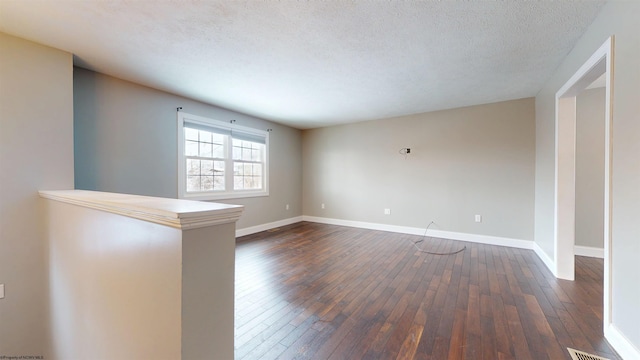 unfurnished room featuring dark wood-type flooring and a textured ceiling