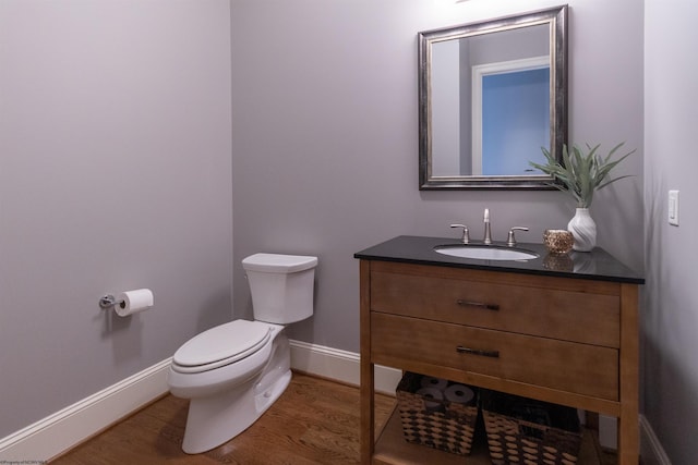 bathroom with wood-type flooring, toilet, and vanity