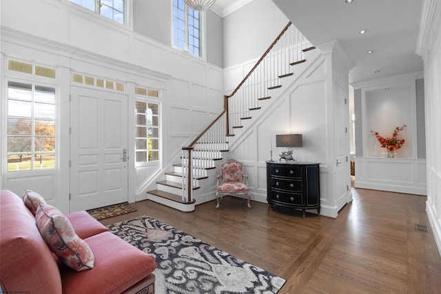 living room with crown molding, a towering ceiling, and dark hardwood / wood-style flooring