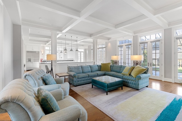 living room with beam ceiling, a wealth of natural light, light hardwood / wood-style floors, and french doors