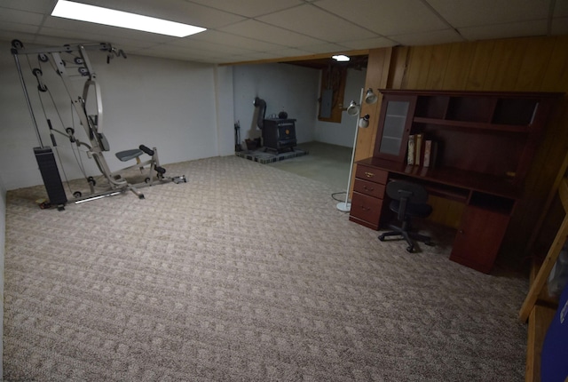 workout room with carpet, a wood stove, a paneled ceiling, and electric panel