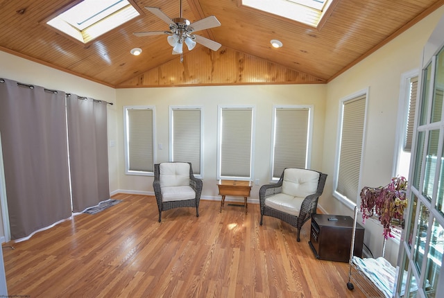 living area featuring ceiling fan, vaulted ceiling with skylight, ornamental molding, light hardwood / wood-style floors, and wooden ceiling