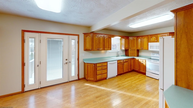 kitchen featuring sink, a textured ceiling, white appliances, and light wood-type flooring