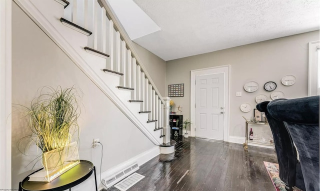 entryway featuring dark wood-type flooring and a textured ceiling