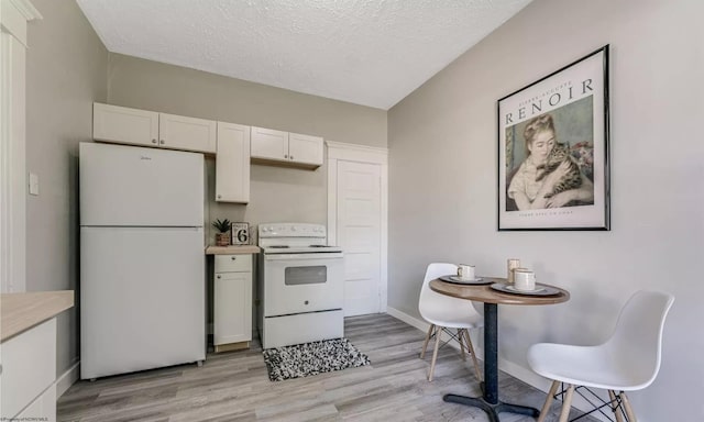 kitchen with white cabinetry, white appliances, and light hardwood / wood-style floors