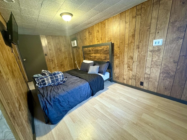 bedroom with light hardwood / wood-style flooring and wood walls