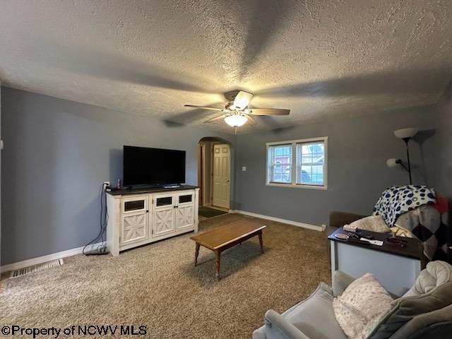 carpeted living room with a textured ceiling and ceiling fan