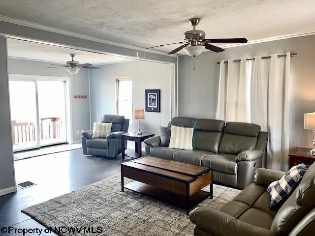 living room featuring ceiling fan, ornamental molding, wood-type flooring, and a textured ceiling