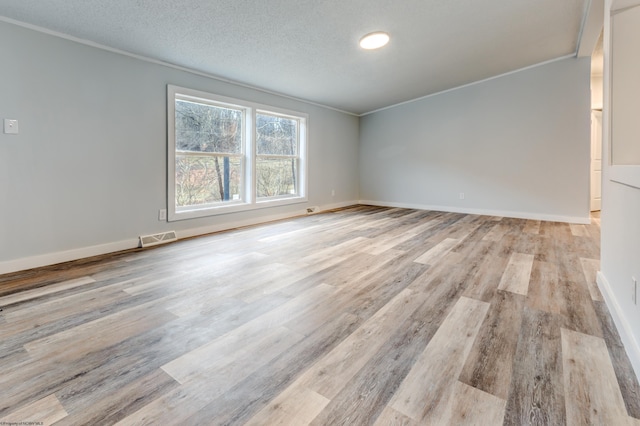 empty room with light hardwood / wood-style flooring, ornamental molding, and a textured ceiling