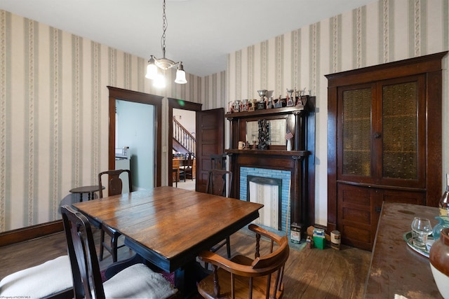 dining room featuring a fireplace, dark hardwood / wood-style flooring, and a notable chandelier