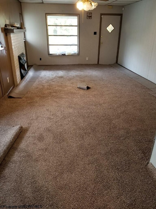 unfurnished living room featuring carpet, ceiling fan, and a fireplace