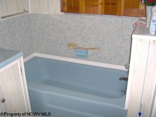 bathroom featuring a washtub and tile walls