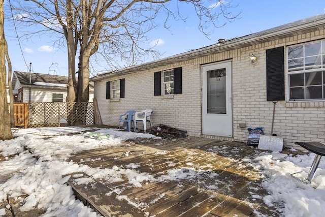 snow covered rear of property featuring a deck