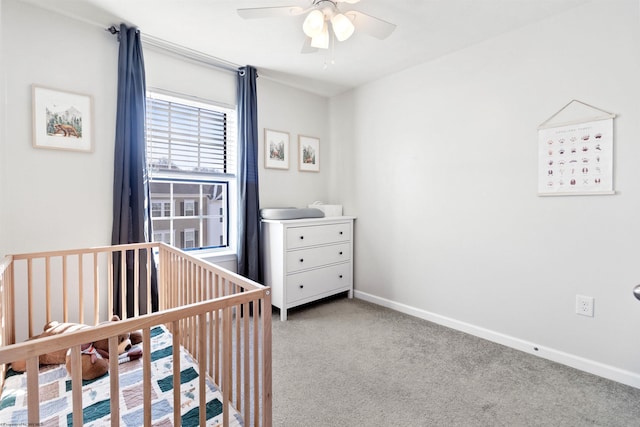 bedroom with a nursery area, light carpet, ceiling fan, and baseboards