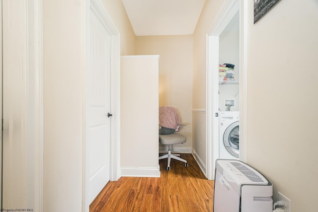 clothes washing area featuring wood finished floors, washer / clothes dryer, baseboards, and laundry area