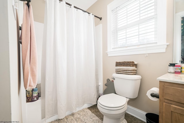 bathroom featuring baseboards, vanity, toilet, and shower / bath combo with shower curtain