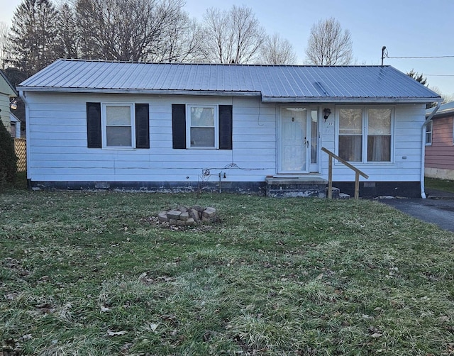 view of front of home with entry steps, metal roof, and a front lawn