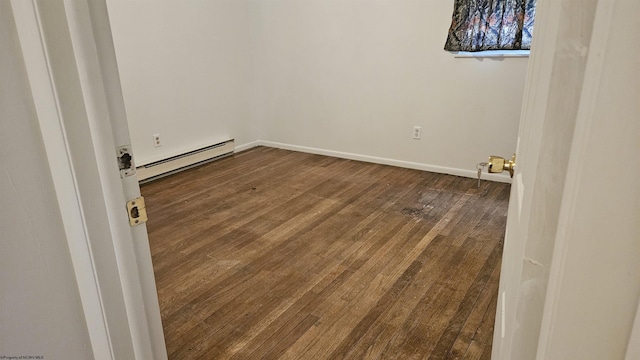 unfurnished room featuring a baseboard heating unit, dark wood-style floors, and baseboards