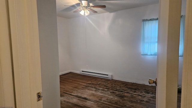 spare room featuring dark wood-style flooring, baseboard heating, and a ceiling fan