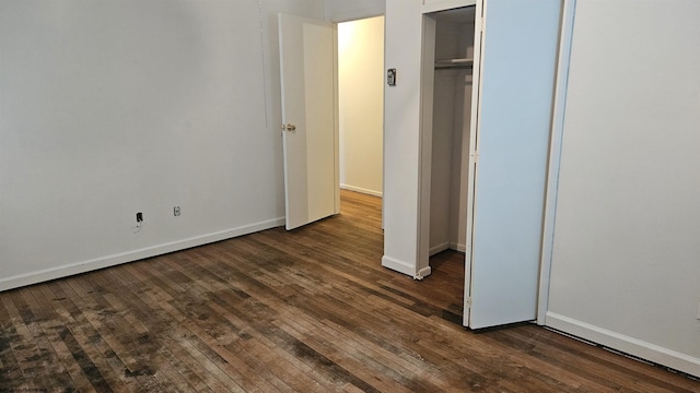 unfurnished bedroom featuring dark wood-style floors, a closet, and baseboards