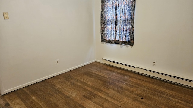 spare room with dark wood-style floors, baseboard heating, and baseboards