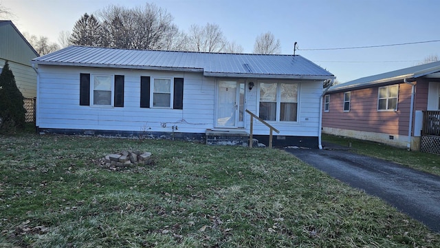 view of front facade with entry steps, metal roof, and a front yard