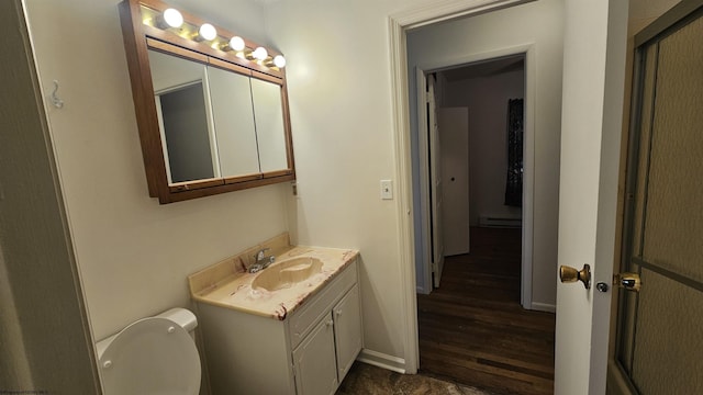 half bath featuring toilet, baseboards, and vanity