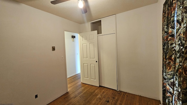 unfurnished bedroom with a closet, dark wood-style flooring, a textured ceiling, and a ceiling fan