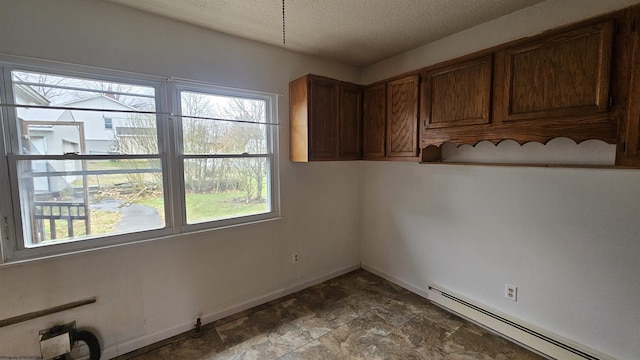 interior space featuring a textured ceiling, baseboard heating, and baseboards