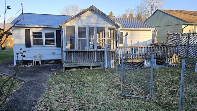 back of house with a yard, a sunroom, metal roof, and a deck