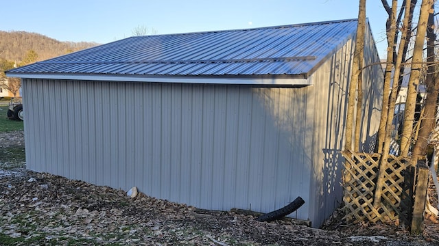 view of property exterior with a mountain view, metal roof, and an outdoor structure