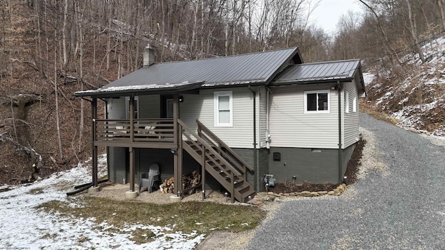 view of front of property with metal roof, a chimney, and stairs