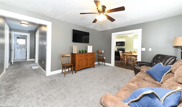 living area with carpet floors, ceiling fan, baseboards, and a textured ceiling